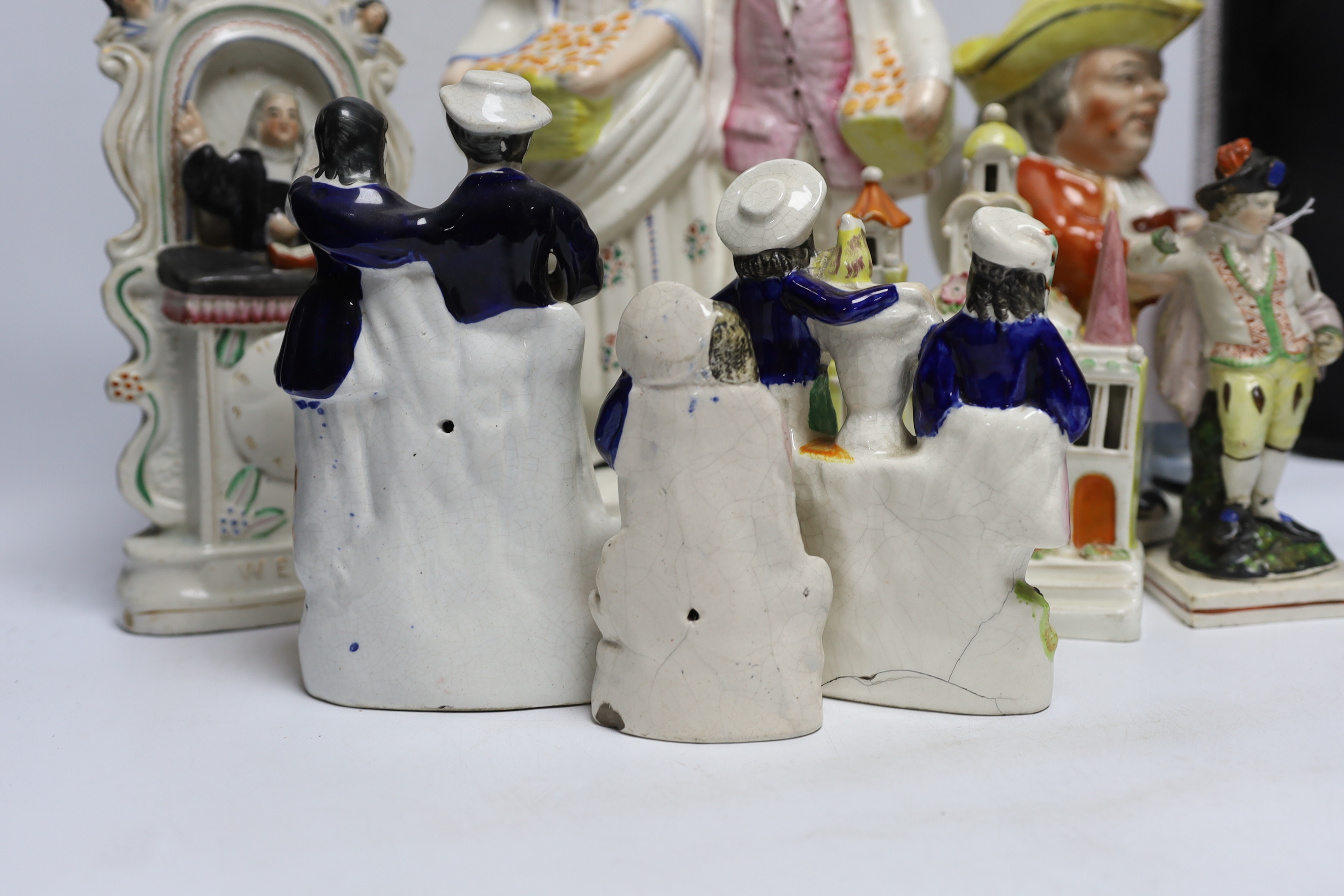 Seven 19th century Staffordshire figure groups including Orange Sellers and Wesley, together with a Toby jug, 35cm high